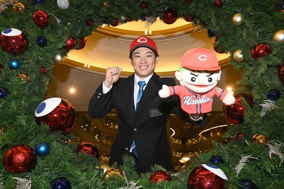 　仮契約を終え、広島グッズを手にポーズをとる近大・勝田（撮影・西田忠信）