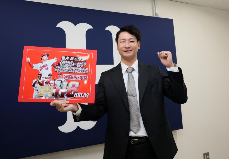 　契約を更改し、ボードを持ってポーズを決める島内（撮影・市尻達拡）