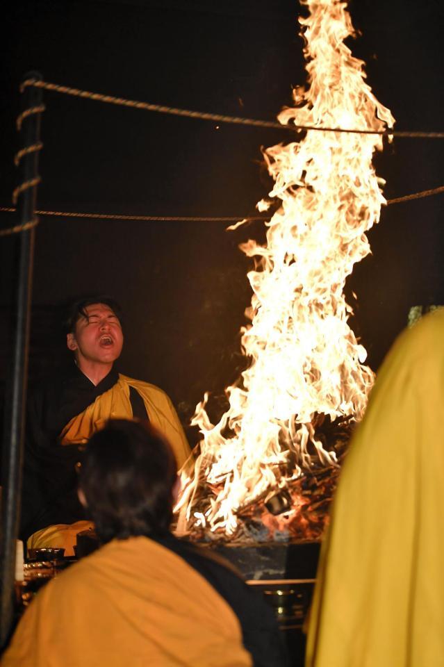 燃えさかる火柱の前で経を唱え続ける会沢（撮影・畠山賢大）