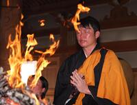 消えゆく炎の前で手を合わせる新井監督（撮影・中田匡峻）