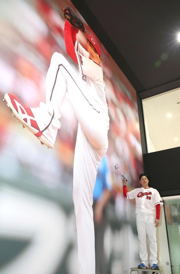 巨大壁画にサインを入れる栗林（撮影・北村雅宏）