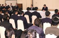 全体ミーティングの席に着く新井監督（右上）