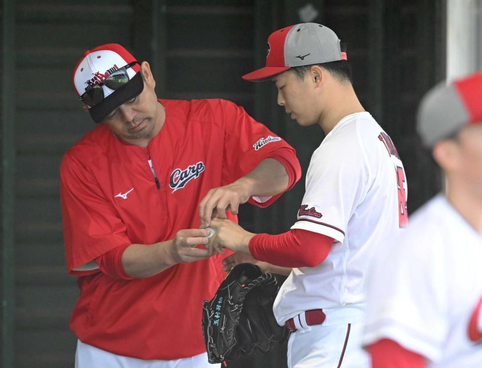 石井投手コーチ（左）から変化球の握りを教わる玉村（撮影・飯室逸平）　