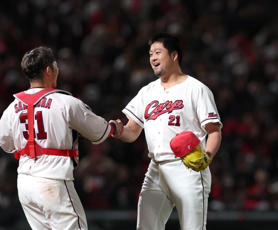 ９回、最後を締めた中崎（右）は坂倉と握手する（撮影・北村雅宏）