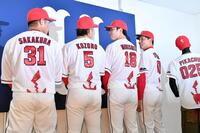 ピカチュウの尻尾がデザインされたイベントユニホームの撮影中に見つめ合う小園（左から２人目）と森下