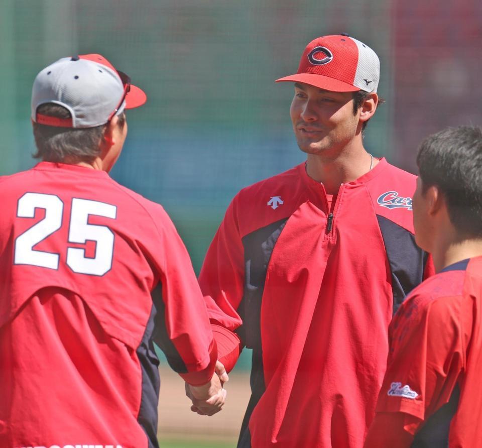 練習中、新井監督（左）と握手を交わすターノック（撮影・北村雅宏）