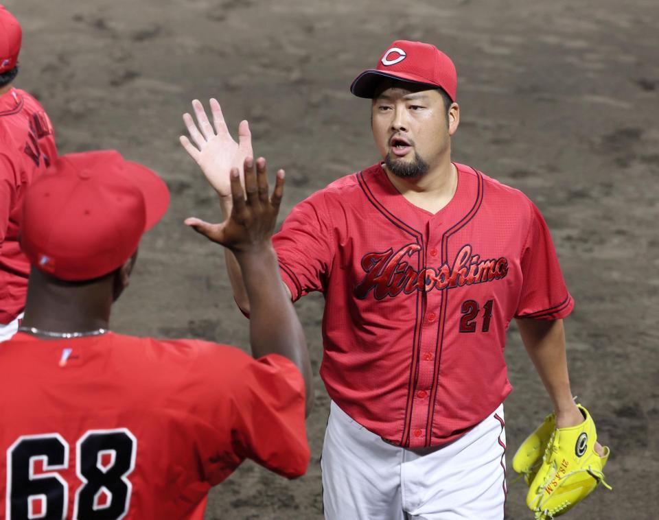 ９回を無失点で乗り切り、ハーン（左）とタッチを交わす中崎（撮影・立川洋一郎）