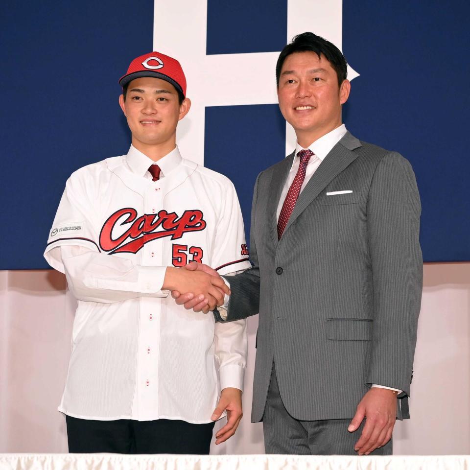 新入団会見で新井監督（右）と握手をする岡本＝２４年