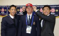 尾形スカウト（左）と下水流スカウト（右）から帽子を被せてもらう広島５巡目指名の明大・光弘帆高（撮影・吉澤敬太）