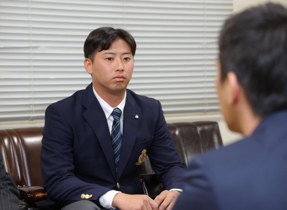 尾形スカウト（手前）から指名あいさつを受ける広島５巡目指名の明大・光弘帆高（撮影・吉澤敬太）