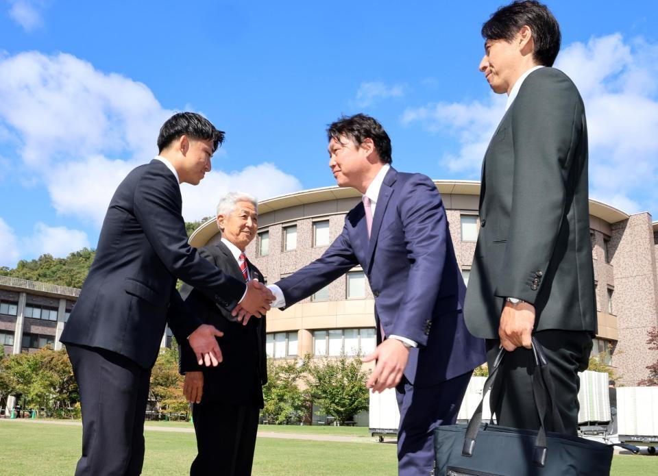 立命大・西野啓也（左）は指名あいさつに訪れた新井監督と握手をする（撮影・山口登）