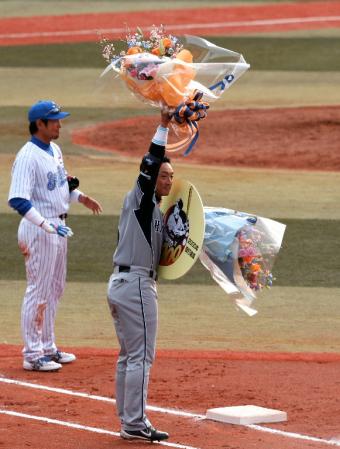 七回、２０００本安打を放った金本はファンに花束を高々と掲げる＝横浜