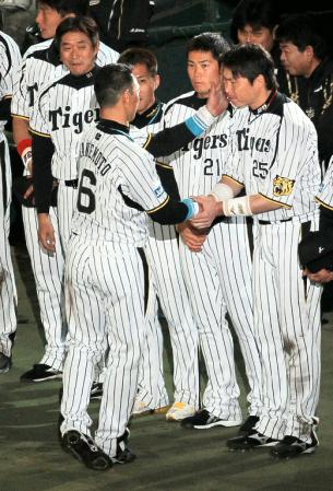 新井（右）の頬に手をやり握手を交わす金本（撮影・高部洋祐）