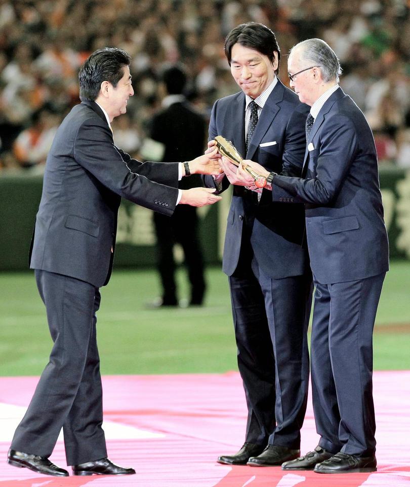 　国民栄誉賞の授与式で安倍首相から記念品の金のバットを贈呈される長嶋茂雄氏。中央は手を添える松井秀喜氏＝５日午後、東京ドーム