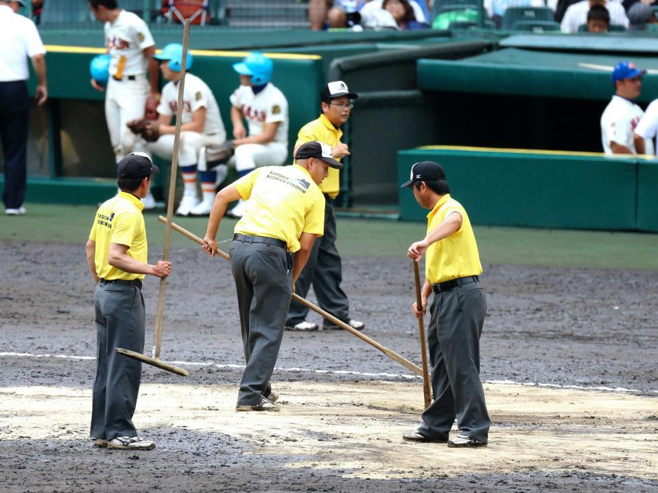 　雨で荒れたグラウンドを整備する阪神園芸の職員たち＝２０１４年８月１６日、甲子園 