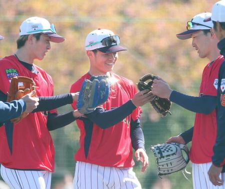 　強化合宿中、源田（右）らとグラブを見せ合う中野（中央）