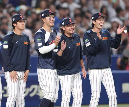 中日に勝利し、笑顔でナインを迎える佐藤輝（左）