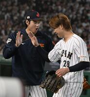 ５回１死、チェコのチェルベンカを右飛に打ち取って降板する高橋を出迎える大谷（左）