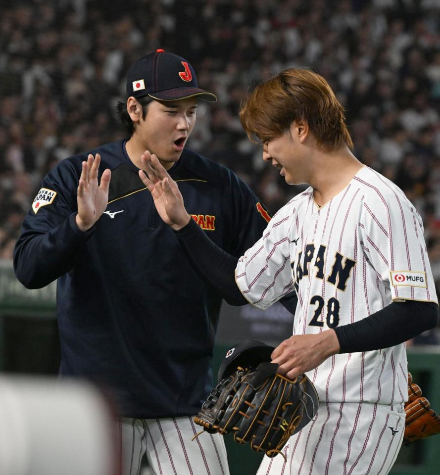 ５回１死、チェコのチェルベンカを右飛に打ち取って降板する高橋を出迎える大谷（左）