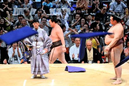 稀勢の里（右）に破れ、座布団が飛び交う中、土俵下を回り込むようにして東の位置へ戻る白鵬