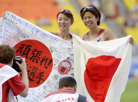 　笑顔で日の丸を手にする福士（右）と４位の木崎良子（共同）