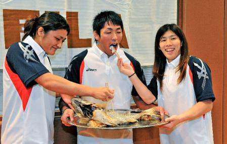 レスリングの存続を祝い、米満達弘（中央）にタイを食べさせる伊調馨（左）と吉田沙保里