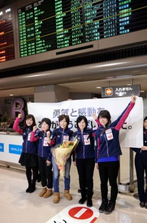 到着ロビーで花束を受け取りポーズを決めるカーリング日本女子代表・北海道銀行の（左から）吉田知那美、苫米地美智子、小笠原歩、船山弓枝、小野寺佳歩＝成田空港（撮影・開出　牧）