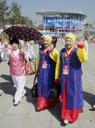 　仁川アジア大会開幕の日を迎え、笑顔で手を振る開会式の出演者。後方は開会式会場の仁川競技場＝１９日、韓国・仁川（共同）