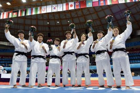 　女子団体で優勝し、金メダルを胸に花束を掲げる日本。左から梅木、稲森、山岸、新井、中村、山本、阿部＝仁川（共同）