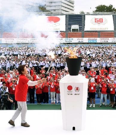 　１９６４年東京五輪の開幕５０周年を記念するイベントで、聖火台に点火する小野清子さん＝１１日午前、東京・駒沢陸上競技場