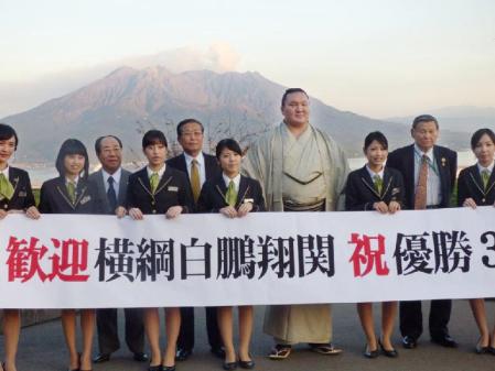 　桜島をバックに関係者と記念写真に納まる横綱白鵬（右から４人目）