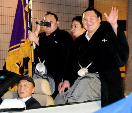 　父親のムンフバトさん（左下）と一緒にパレードの車に乗り、笑顔で手を振る白鵬（右）＝撮影・堀内翔　