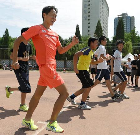 　北京市内の日本人学校を訪問し、小中学生と交流する男子20キロ競歩代表の鈴木雄介（手前）＝25日（共同）