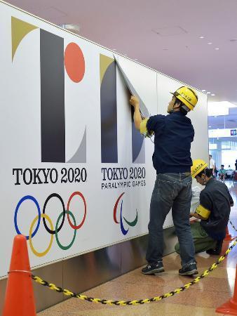 　作業員にはがされる、羽田空港国際線ターミナルの白紙撤回された東京五輪・パラリンピックのエンブレム＝２日午後