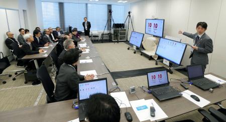 　東京五輪・パラリンピックの大会公式エンブレムのデザインを審査するにあたり、事務局スタッフから説明を受ける審査員ら（左側）＝１５日午前、東京都港区（代表撮影）