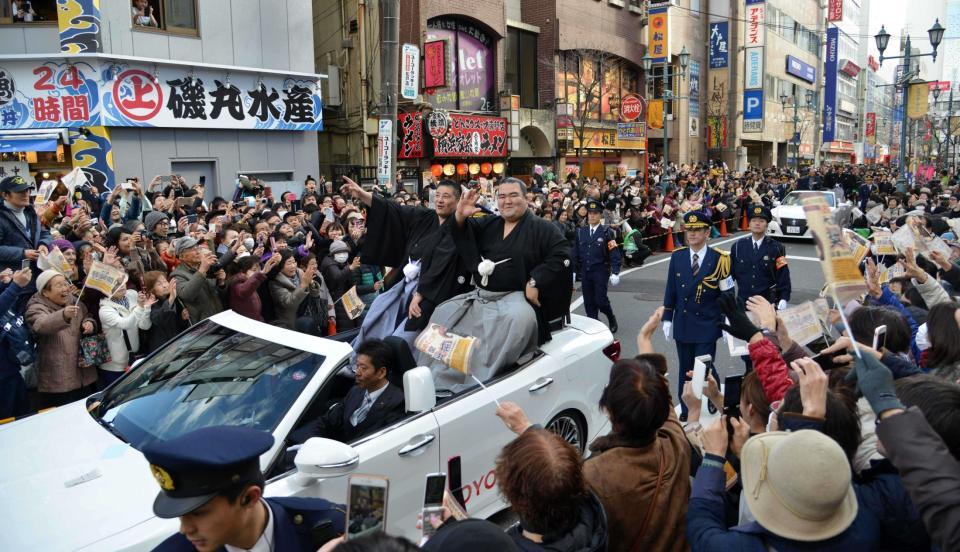 　多くのファンが駅前の沿道を埋め尽くすなか、笑顔で声援に応える琴奨菊（右）と佐渡ケ嶽親方