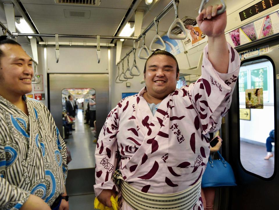 　電車に乗り笑顔を見せる佐藤