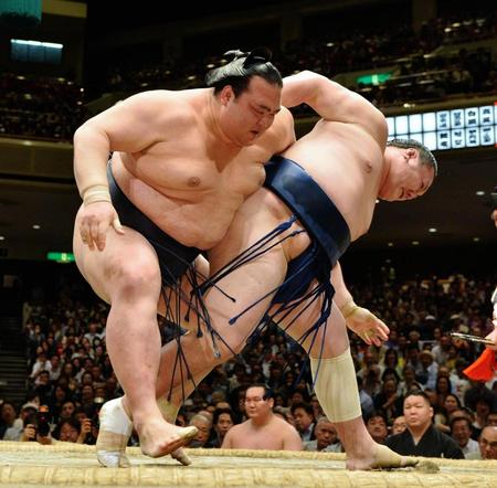 勢（右）の投げをこらえ送り出しで全勝を守った稀勢の里＝両国国技館（撮影・園田高夫）