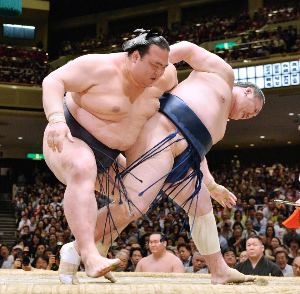 　勢（右）の投げをこらえる稀勢の里。送り出しで全勝を守った（撮影・園田高夫）