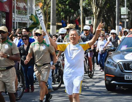 　リオデジャネイロ五輪の聖火リレーで、トーチを手に沿道の声援に応える小川彰夫さん＝２４日、サンパウロ（共同）