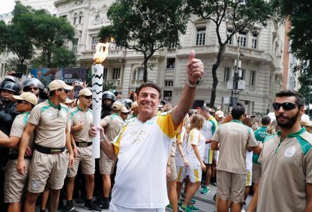 　リオデジャネイロ市で始まった聖火リレーで、トーチを手に笑顔の聖火ランナー＝３日（共同）