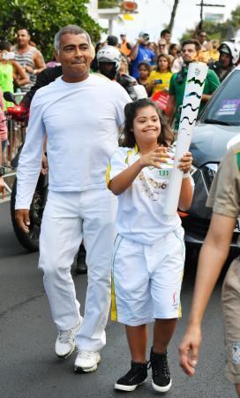 　リオデジャネイロ市の聖火リレーで、女の子のランナーに伴走する元サッカーブラジル代表のロマーリオ氏＝４日（共同）