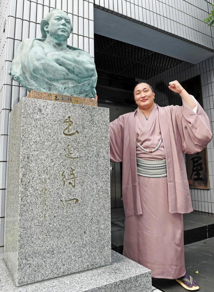 　先代・九重親方の銅像の横でガッツポーズを見せる千代翔馬