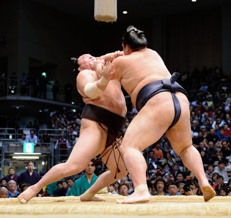 稀勢の里（右）の突っ張りにのけぞる白鵬＝福岡国際センター