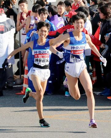 　１位でたすきを渡し、笑顔の神奈川大・鈴木健吾（左）＝共同＝代表撮影