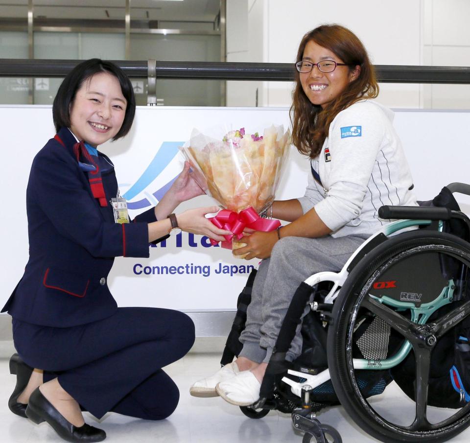 　帰国し、航空会社スタッフから花束を受け取る車いすテニス女子の上地結衣＝成田空港