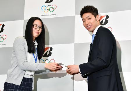 　ブリヂストンの入社式を終えて、報道関係者と名刺交換するリオ五輪競泳金メダルの萩野公介選手＝３日午前、東京都港区