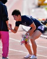 男子１００Ｍ決勝で優勝し、花束をくれた女子スタッフにお礼のサインをする桐生祥秀