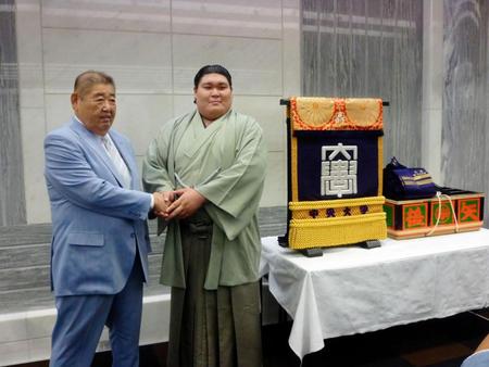 中大から贈呈された化粧まわしの前で握手する矢後（右）と平岩監督