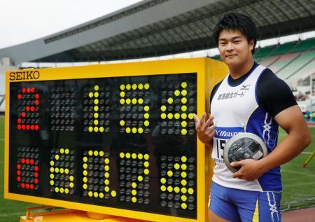 　男子円盤投げで６０メートル７４の日本新記録を樹立し、ボードの前でポーズをとる堤雄司＝ヤンマースタジアム長居